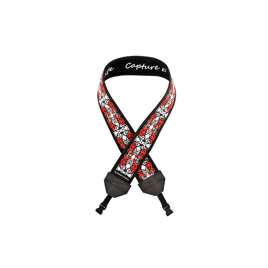 Photo of a camera strap with red and white scrolls on a black background and quick-release webbing